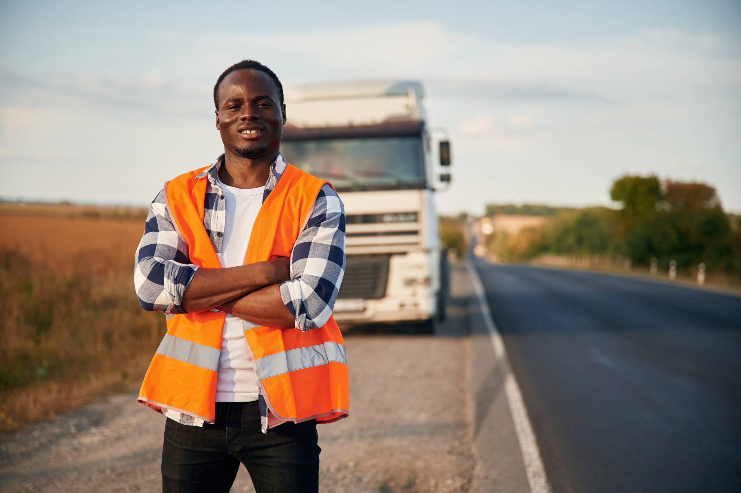 Truck is behind. Black man is standing on the road.